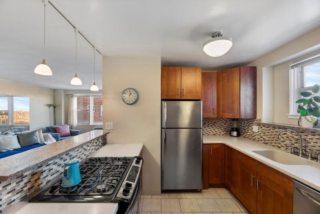 kitchen with backsplash, appliances with stainless steel finishes, light countertops, and a sink