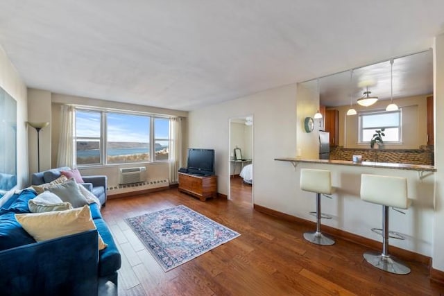 living area featuring a baseboard heating unit, wood finished floors, and baseboards