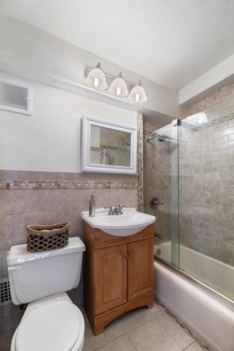 full bath featuring tile patterned flooring, visible vents, tile walls, toilet, and vanity