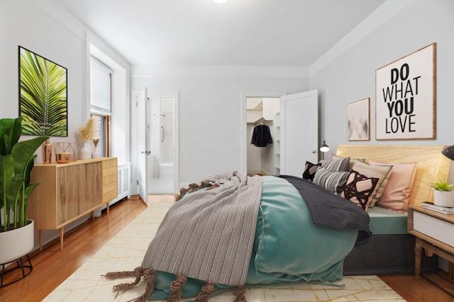 bedroom with ensuite bath and light hardwood / wood-style flooring