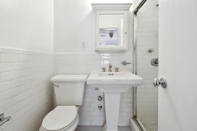 bathroom with tile walls, toilet, and a tile shower