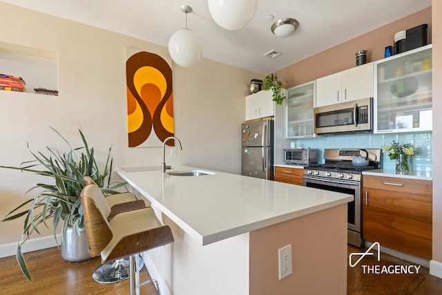 kitchen with a breakfast bar, a sink, backsplash, appliances with stainless steel finishes, and light countertops