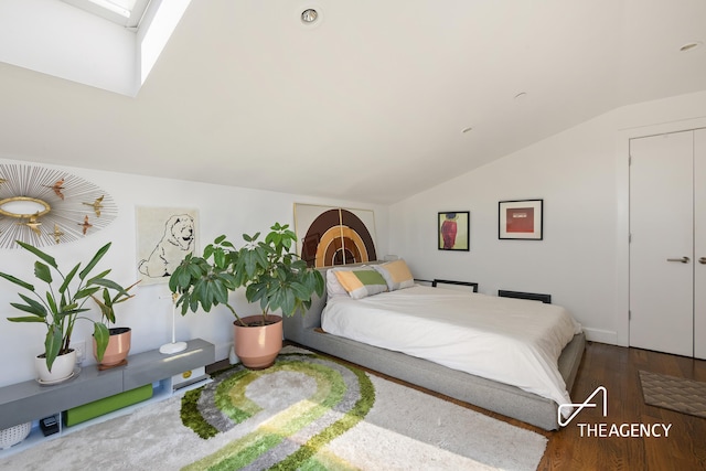 bedroom featuring lofted ceiling with skylight and wood finished floors