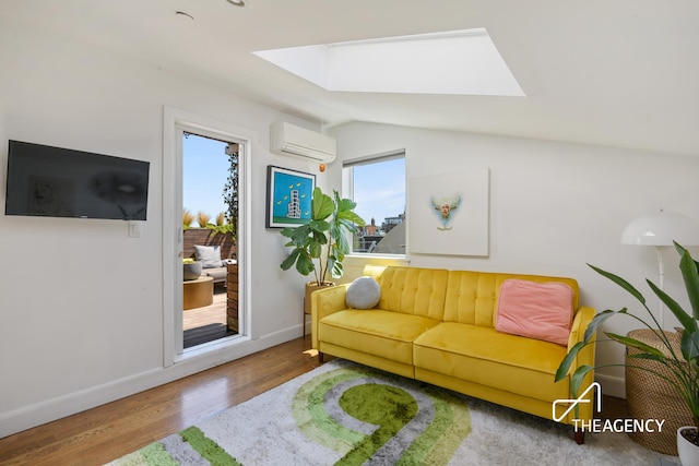 living room with vaulted ceiling with skylight, a wall mounted air conditioner, baseboards, and wood finished floors