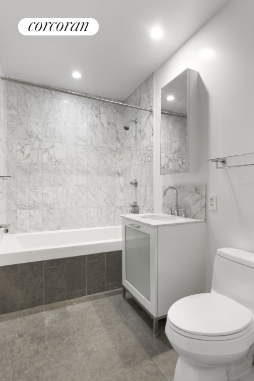 full bathroom with tiled shower / bath combo, vanity, tile walls, and toilet