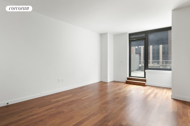 empty room featuring wood finished floors, visible vents, and baseboards