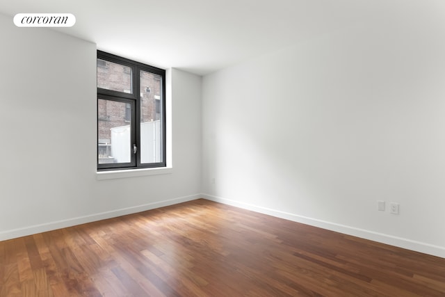 empty room featuring wood finished floors, visible vents, and baseboards