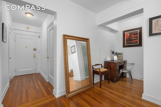 corridor with hardwood / wood-style floors and baseboards