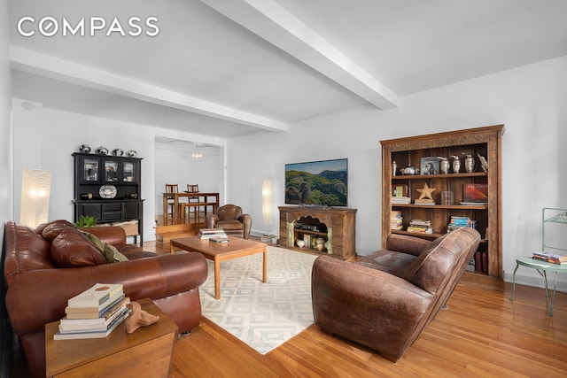 living room with light wood-type flooring, beam ceiling, and baseboards