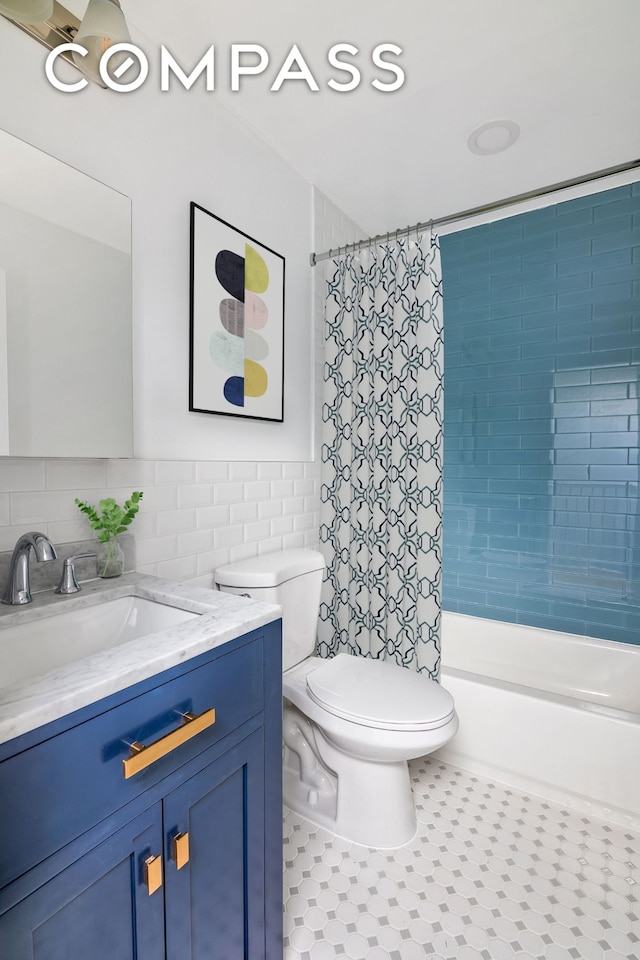 bathroom featuring vanity, shower / bathtub combination with curtain, a wainscoted wall, tile walls, and toilet