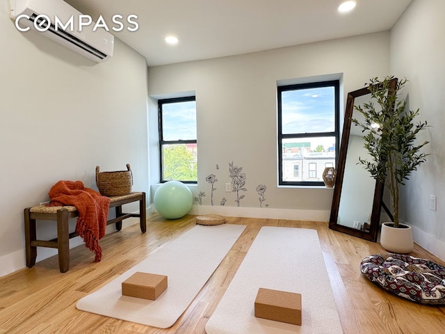 exercise room with recessed lighting, baseboards, a wall unit AC, and wood finished floors