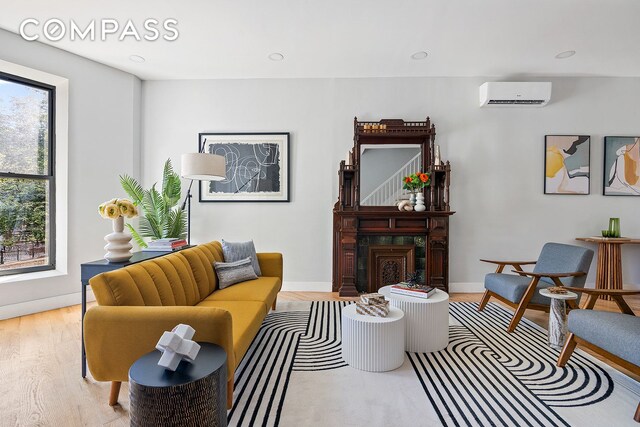 living room featuring a wall unit AC and light wood-type flooring