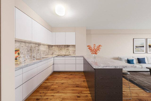 kitchen with a breakfast bar, white cabinets, light hardwood / wood-style floors, and kitchen peninsula