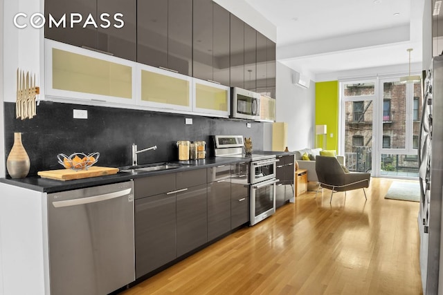 kitchen with tasteful backsplash, sink, light wood-type flooring, and appliances with stainless steel finishes