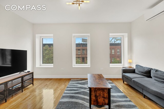 living area with light hardwood / wood-style floors and a wall mounted AC