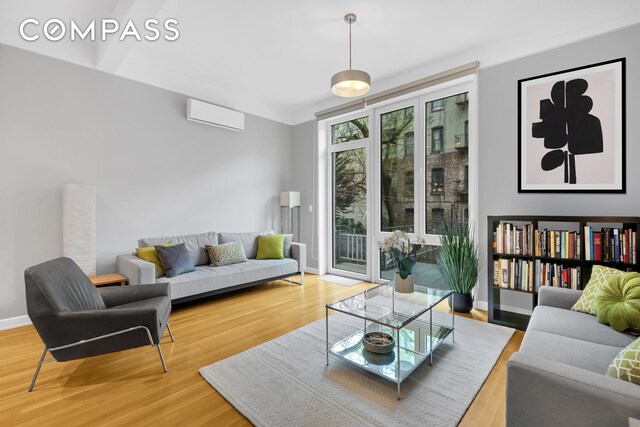 living room with an AC wall unit and hardwood / wood-style floors