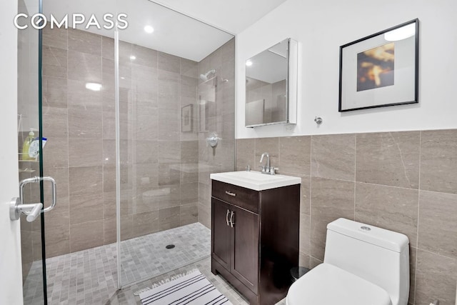 bathroom with vanity, an enclosed shower, tile walls, and toilet