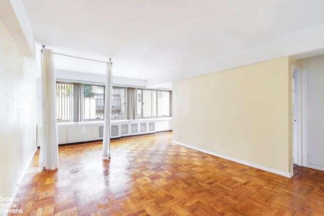 spare room featuring parquet flooring and radiator