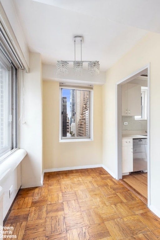 unfurnished dining area featuring light parquet flooring and a chandelier