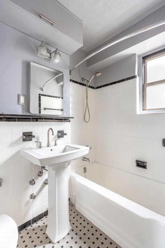 bathroom featuring tile walls, tiled shower / bath combo, toilet, and a textured ceiling