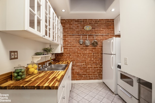 kitchen featuring sink, white appliances, white cabinets, brick wall, and wood counters