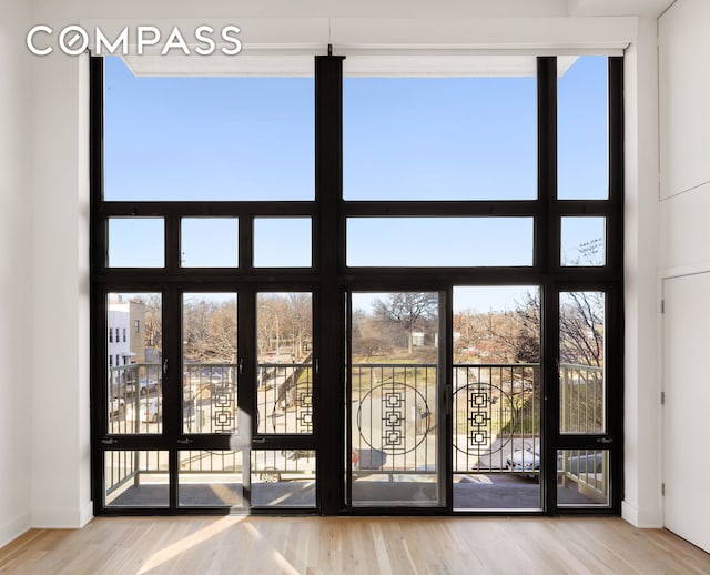 entryway with a wealth of natural light, baseboards, a wall of windows, and wood finished floors