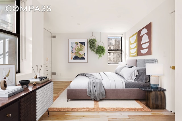 bedroom with light wood finished floors, visible vents, and baseboards