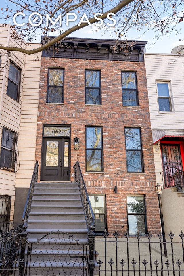 multi unit property with brick siding and a fenced front yard