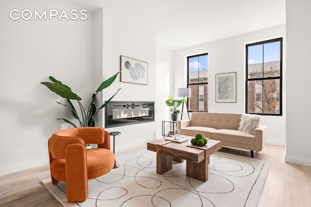 living room with baseboards, wood finished floors, and a glass covered fireplace