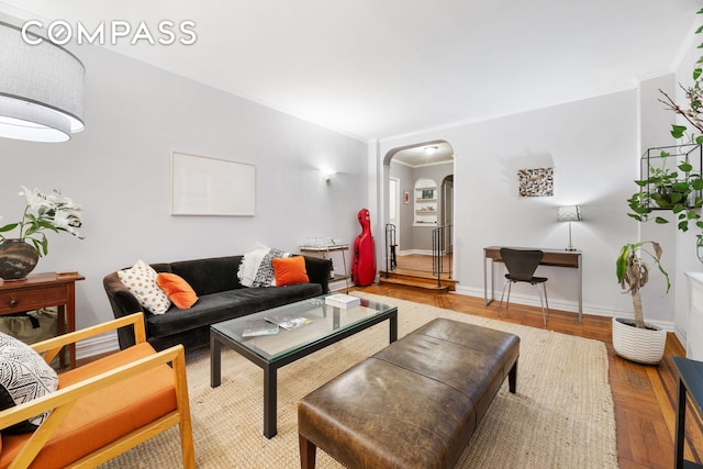 living area with baseboards, arched walkways, light wood-style flooring, and crown molding