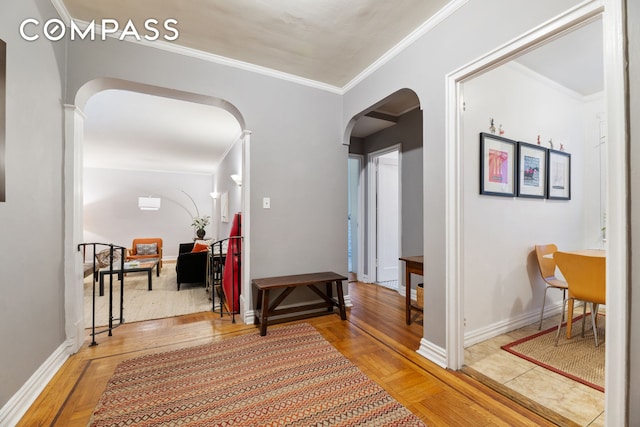 corridor with arched walkways, crown molding, and baseboards