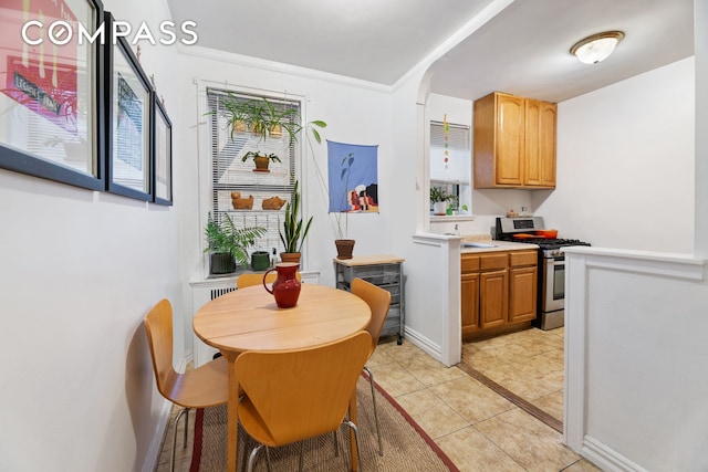95 Park Ter E Unit 3B, New York City, NY 10034 - kitchen featuring stainless steel range with gas cooktop, light countertops, light tile patterned floors, baseboards, and brown cabinets