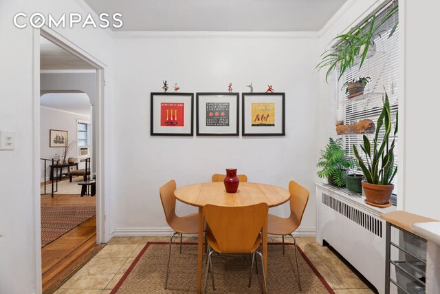 tiled dining area featuring radiator and ornamental molding