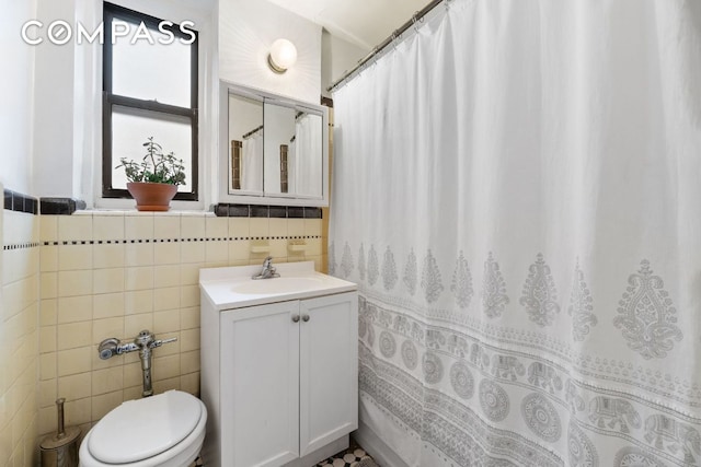 bathroom featuring vanity, tile walls, and toilet