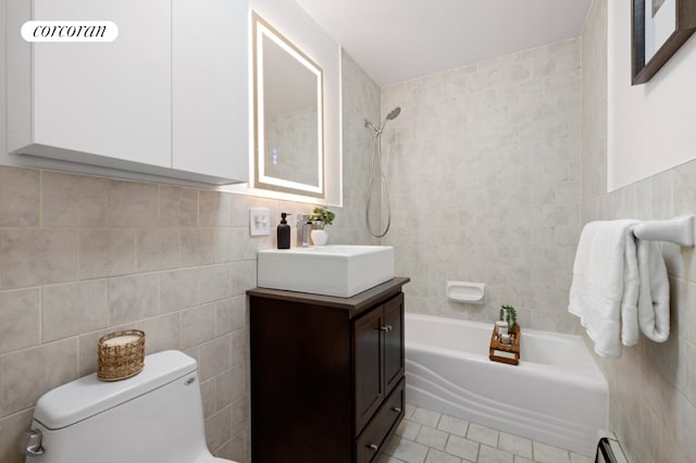 full bathroom with a baseboard radiator, tile walls, tiled shower / bath combo, vanity, and toilet