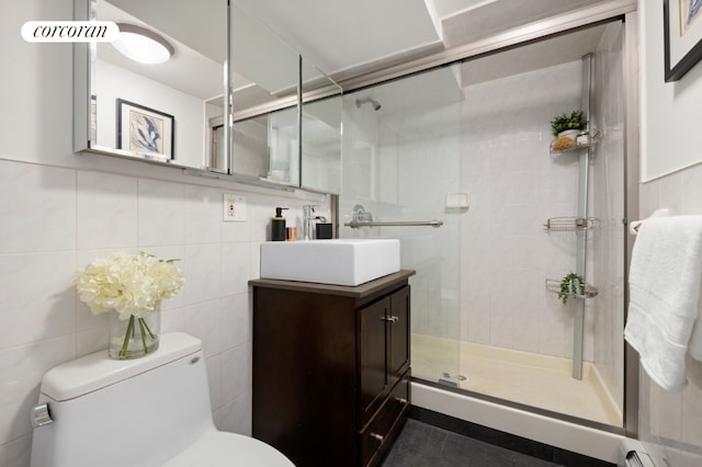 bathroom with a shower with door, tile walls, vanity, a baseboard radiator, and toilet