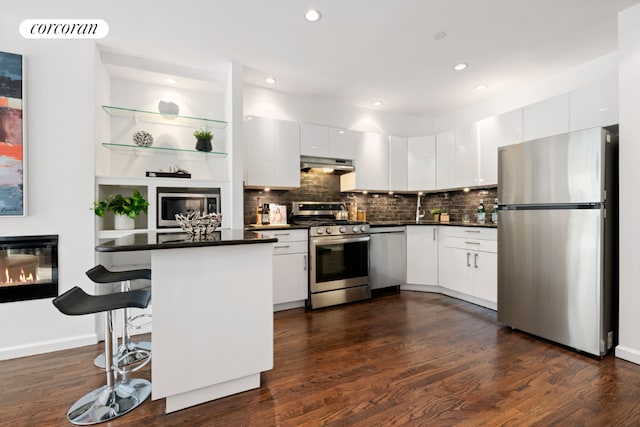 kitchen featuring appliances with stainless steel finishes, a breakfast bar, white cabinets, and kitchen peninsula