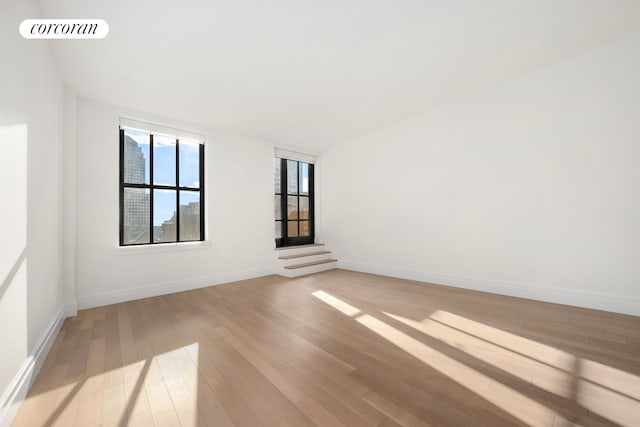 unfurnished room with light wood-style flooring, visible vents, and baseboards