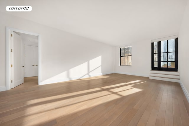 unfurnished living room featuring visible vents, baseboards, and wood finished floors