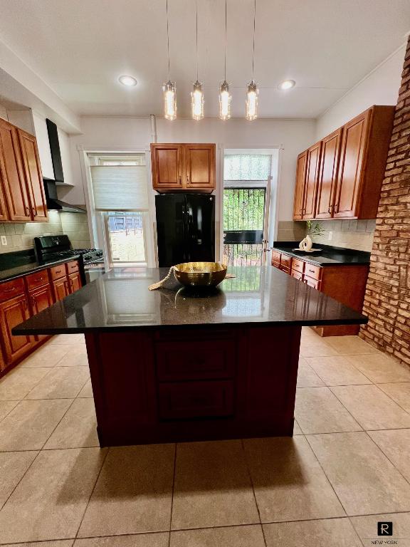 kitchen featuring black appliances, backsplash, dark countertops, and a kitchen island