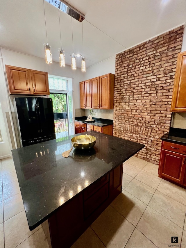 kitchen with light tile patterned floors, pendant lighting, a kitchen island, freestanding refrigerator, and brick wall