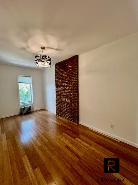 unfurnished room with baseboards, wood-type flooring, and radiator