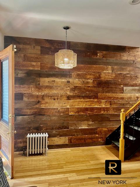 bar featuring hardwood / wood-style flooring, radiator heating unit, and wooden walls