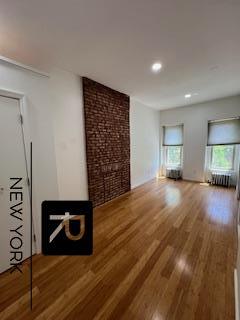 unfurnished living room with brick wall and wood finished floors