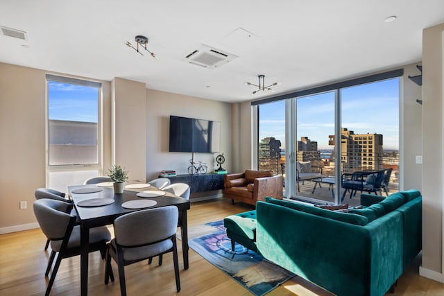 living room featuring baseboards, floor to ceiling windows, visible vents, and wood finished floors