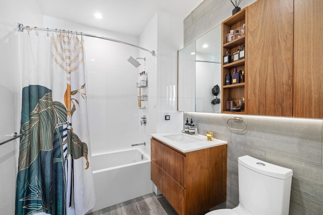 full bath with shower / bath combo, tile walls, toilet, and vanity