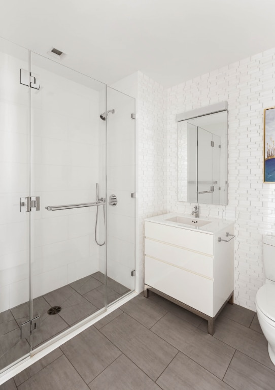 bathroom featuring vanity, an enclosed shower, and toilet