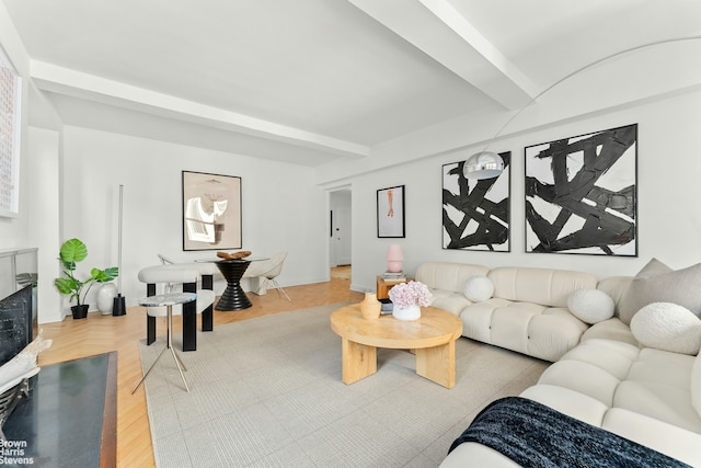 living area featuring parquet flooring, a fireplace, and beamed ceiling