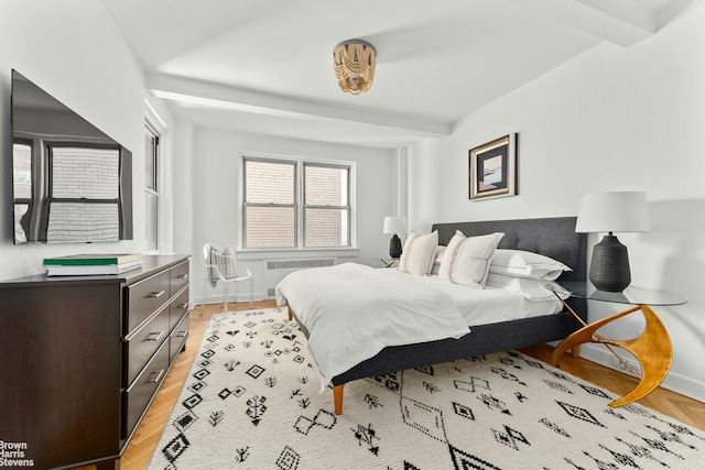 bedroom with baseboards, light wood finished floors, and radiator