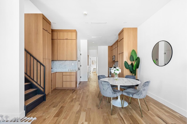 dining area featuring stairs, baseboards, and light wood-type flooring